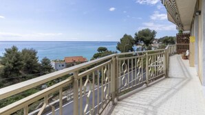 A balcony with a view of the sea, a tiled floor, and a railing.