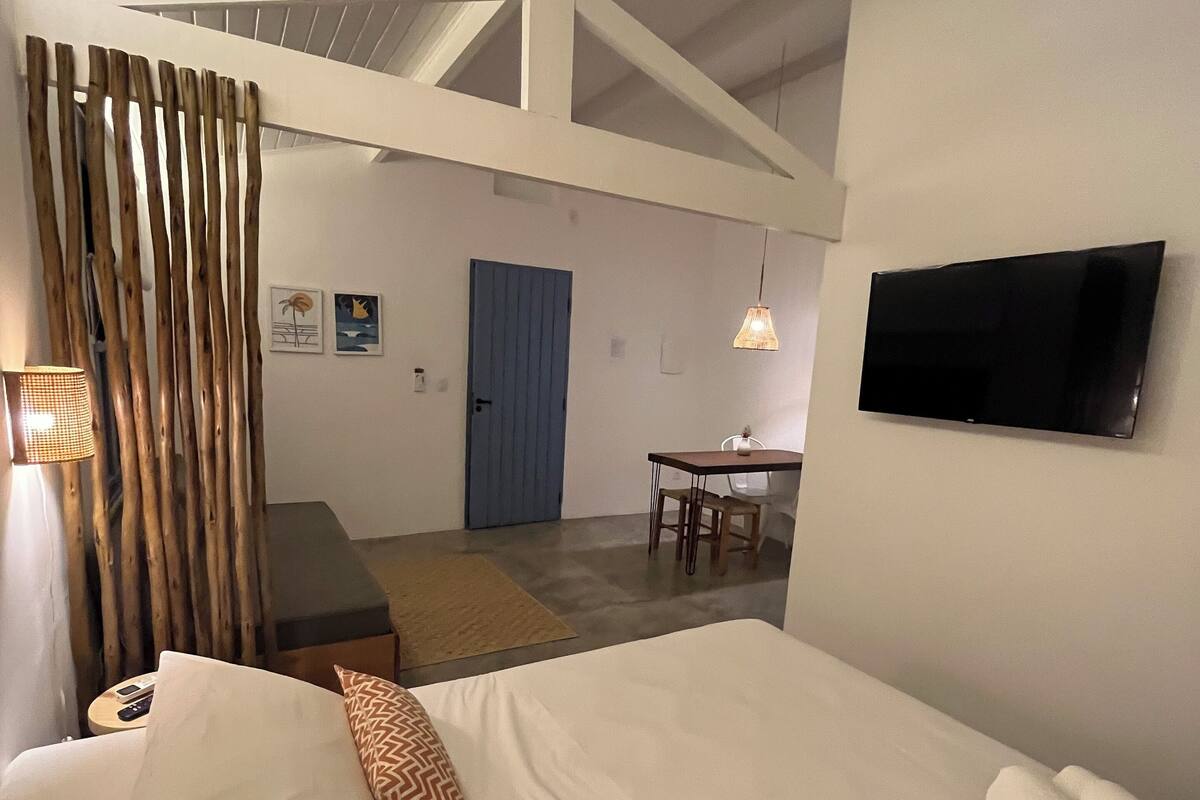 A bedroom with a bed, a TV, a desk, and a chair.