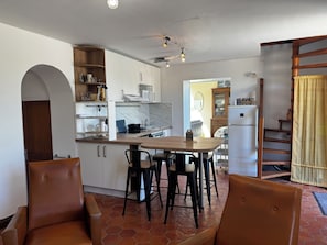 A kitchen with white cabinets, a wooden dining table, and two leather chairs.