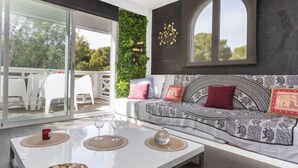 A modern living room with a white sofa, a glass coffee table, and a view of the outdoors. - Apartment Edison by Interhome (Peñiscola)