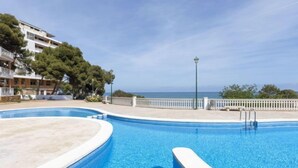 A swimming pool with a curved edge, a white fence, and a view of the sea. - Apartment Edison by Interhome (Peñiscola)
