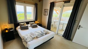 A bedroom with a bed, bedside tables, a nightstand, a window, and a door leading to a balcony. - Seaviews AC viilla 8 people near beach (Son Bou)