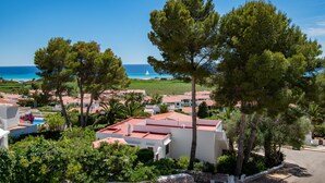 A coastal residential area with white buildings, red-tiled roofs, and lush greenery. - Seaviews AC viilla 8 people near beach (Son Bou)