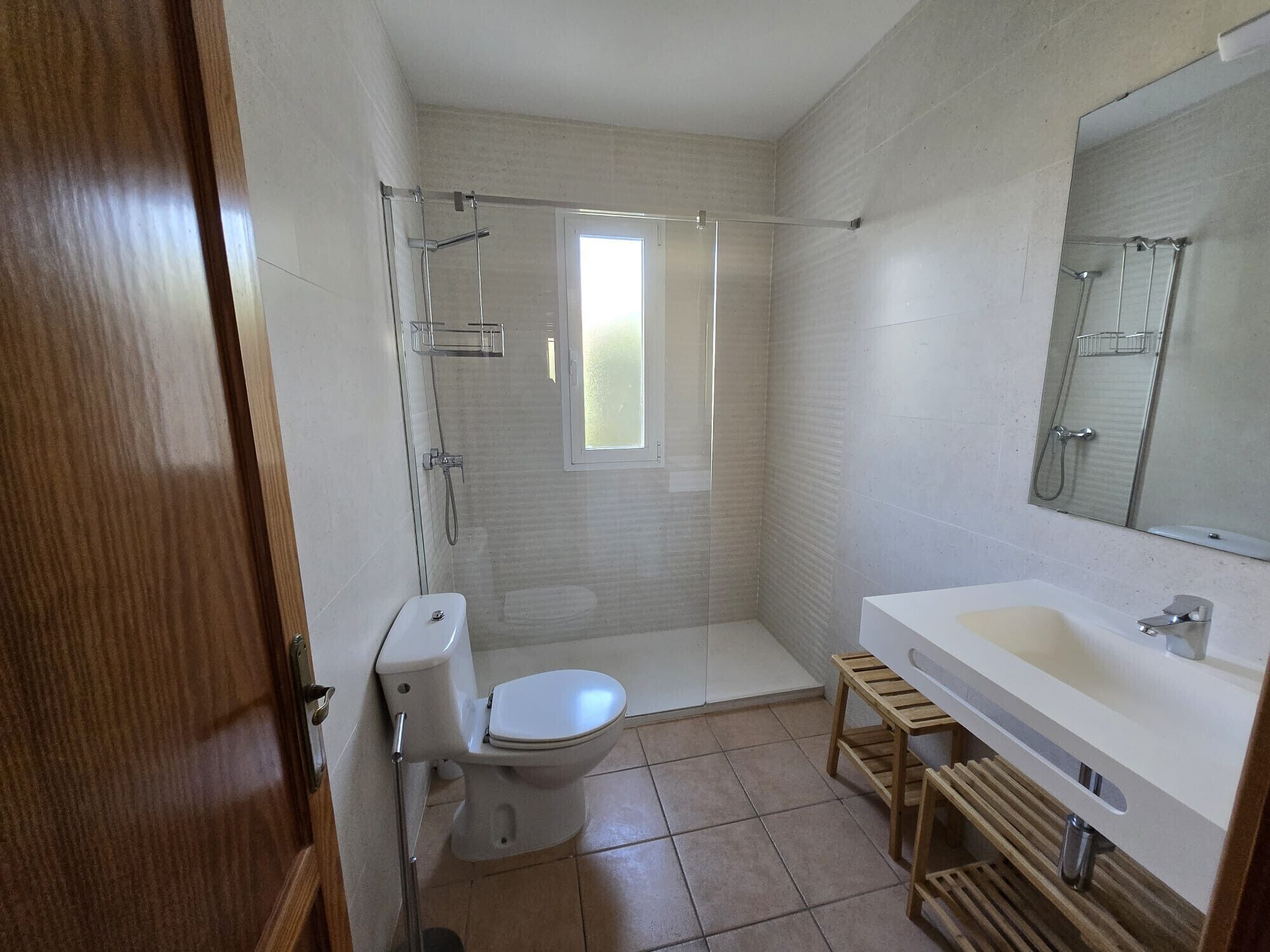 A modern bathroom with a toilet, shower, and sink.