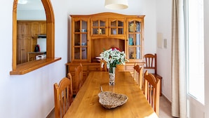 Ein Essbereich mit einem Holztisch, Stühlen, einer Vase mit Blumen und einem Holzschrank mit Glastüren.