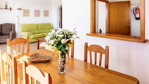 Ein Essbereich mit einem Holztisch, Stühlen, einer Vase mit Blumen und einem Spiegel an der Wand.