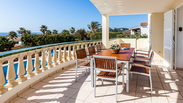Eine Terrasse mit Tisch und Stühlen und Blick auf das Meer, mit gefliestem Boden.