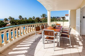 Una terraza con mesa y sillas, vista al mar y suelo de baldosas.