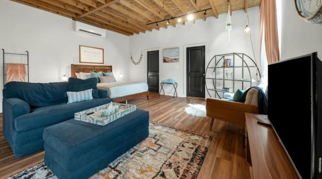 A modern living room with a blue sofa, a coffee table, a TV, and a bookshelf.