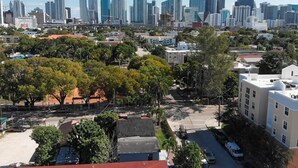 Un paisaje urbano con modernos rascacielos al fondo y una combinación de edificios residenciales y comerciales en primer plano.