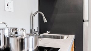 Una cocina con electrodomésticos de acero inoxidable, un grifo moderno y una pared negra.