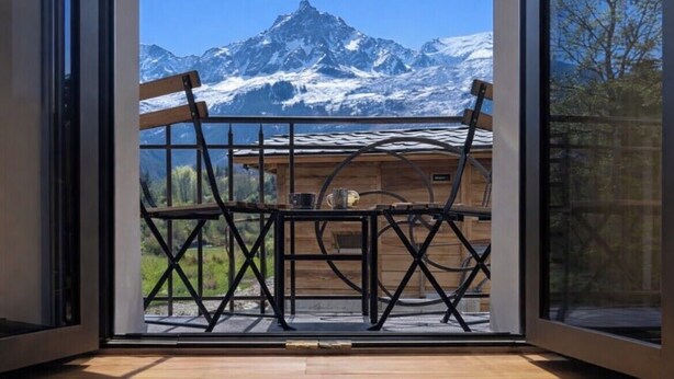 A wooden cabin with a balcony, a table, and chairs. - Apartment overlooking Mont Blanc with parking (Chamonix-Mont-Blanc)