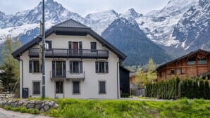 A two-story chalet with a balcony, set against a backdrop of snow-capped mountains. - Apartment overlooking Mont Blanc with parking (Chamonix-Mont-Blanc)