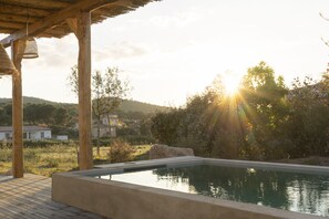 Una piscina con bordo in legno e un pergolato.