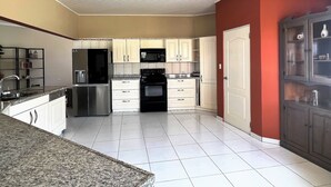 Una cocina con armarios blancos, un refrigerador negro, un microondas y una estufa.
