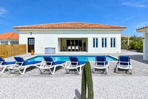 A modern house with a swimming pool, white walls, and a tiled roof.