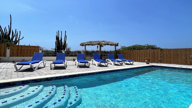 Una piscina con sillas reclinables azules y una valla de madera.
