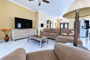 A modern living room with a flat-screen TV, a sofa, a coffee table, and a lamp.