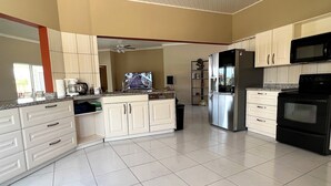 Una cocina amplia con armarios blancos, un refrigerador de acero inoxidable, un microondas y un horno negro.