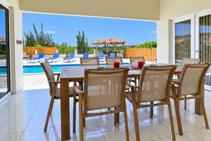 Area ristoro a bordo piscina con tavolo e sedie, una piscina e vista sulla zona piscina.
