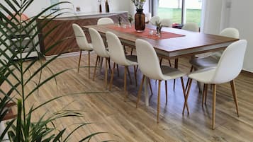 A modern dining area with a wooden table, white chairs, and a central vase with flowers.