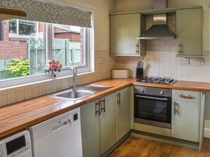 A kitchen with a dishwasher, stove, sink, and cabinets.