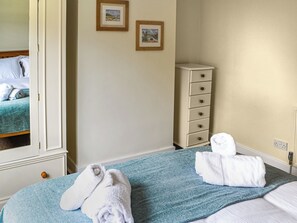 A hotel room with a bed, a dresser, and two framed pictures on the wall.