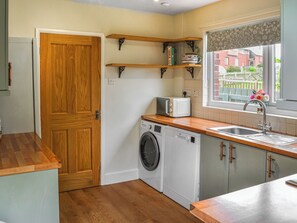 A compact kitchen with a washing machine, a microwave, and a sink.