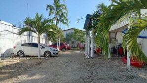 Un camino de grava que lleva a un edificio blanco con un coche rojo estacionado cerca.