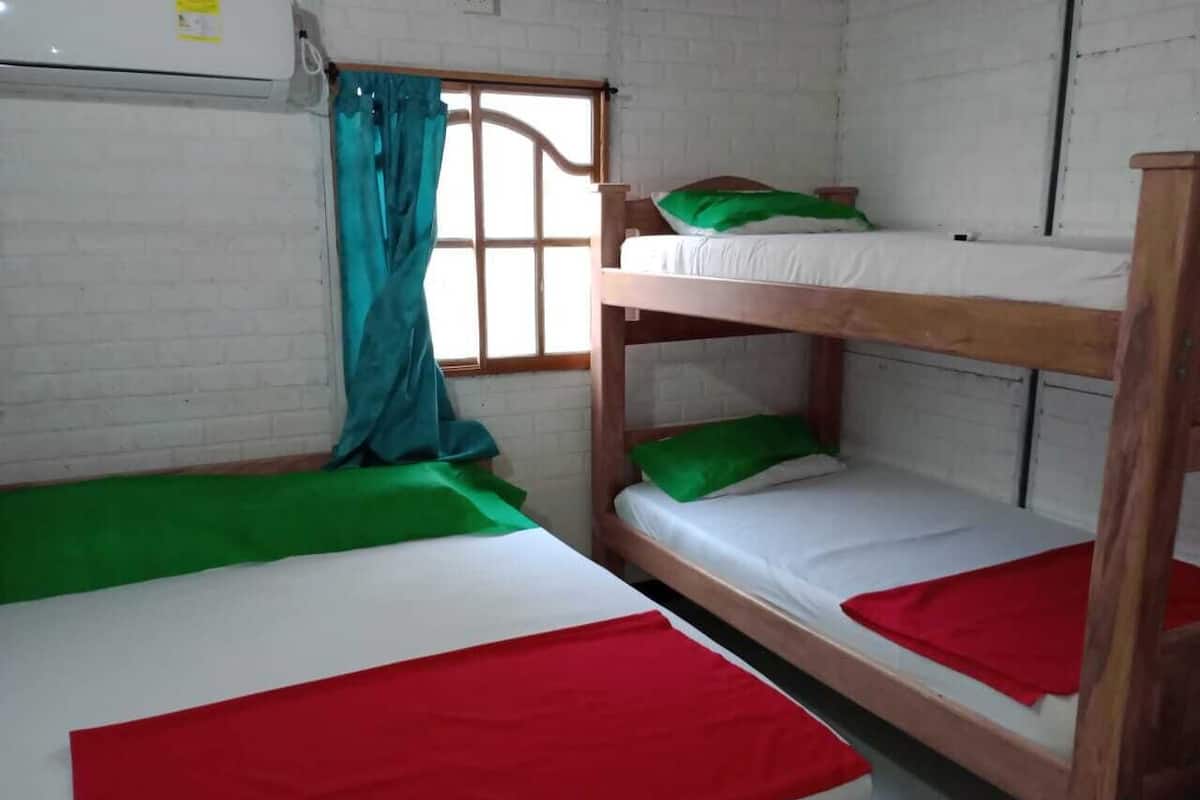 A dormitory room with two bunk beds, each with a red and green bedspread.