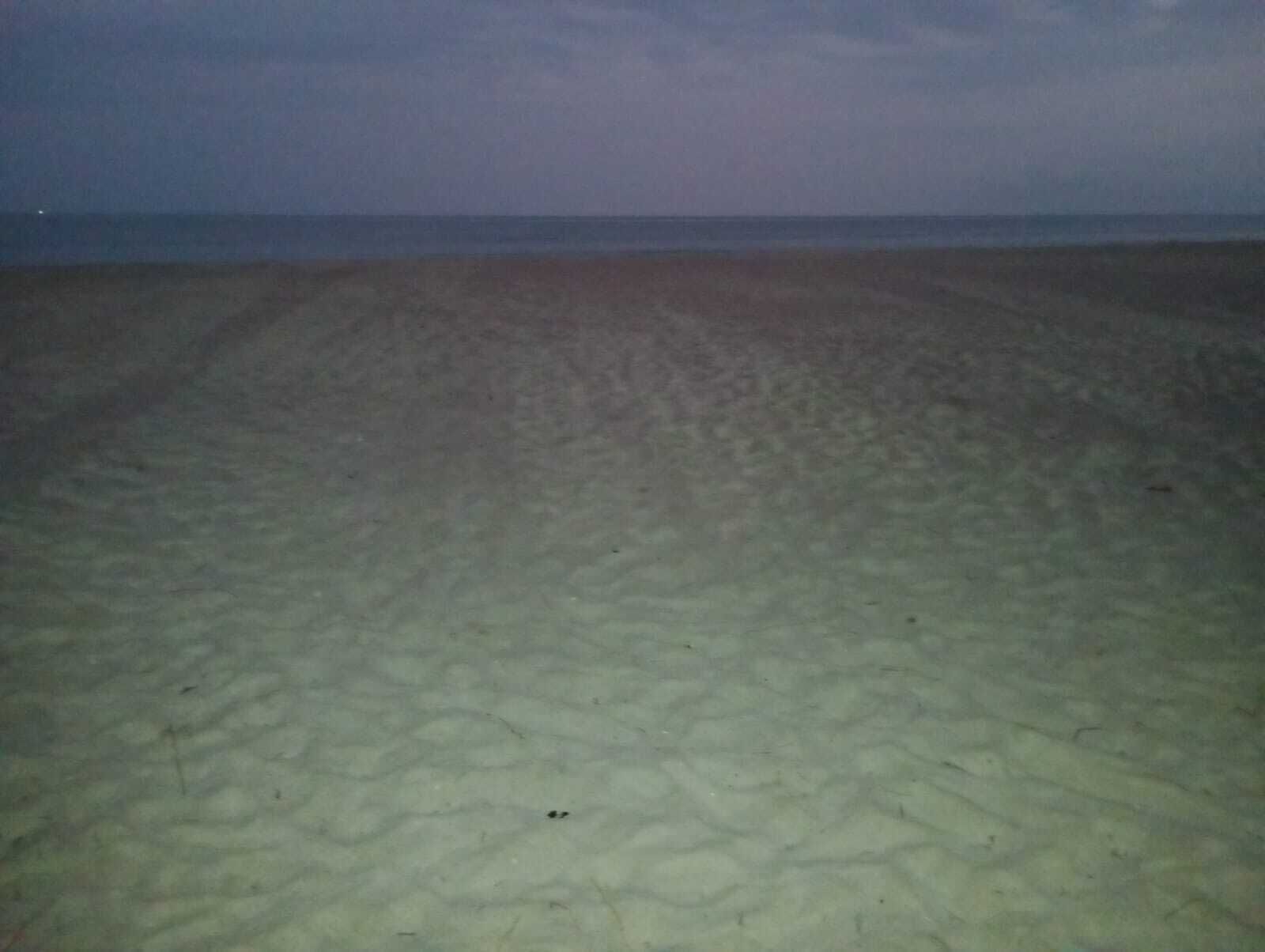 Une plage de sable fin, avec une mer calme en arrière-plan.