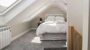 A bedroom with a skylight, a bed, a nightstand, and a radiator. - Bwthyn Cae'r Efail (Rhosgoch)