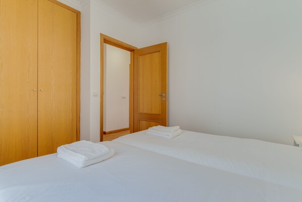 A hotel room with two beds, wooden wardrobes, and a door leading to another room. - Esfera I (Santa Cruz)