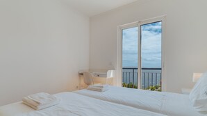 A hotel room with two beds, a desk, a chair, a window with a view of the sea, and a balcony. - Esfera I (Santa Cruz)