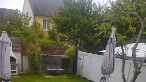 A backyard with a wooden deck, a barbecue grill, and a table with chairs. - Le Petit Viry, à 20min D'orly (Viry-Châtillon)