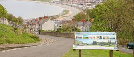 A coastal road with a signboard and a view of a town and beach.