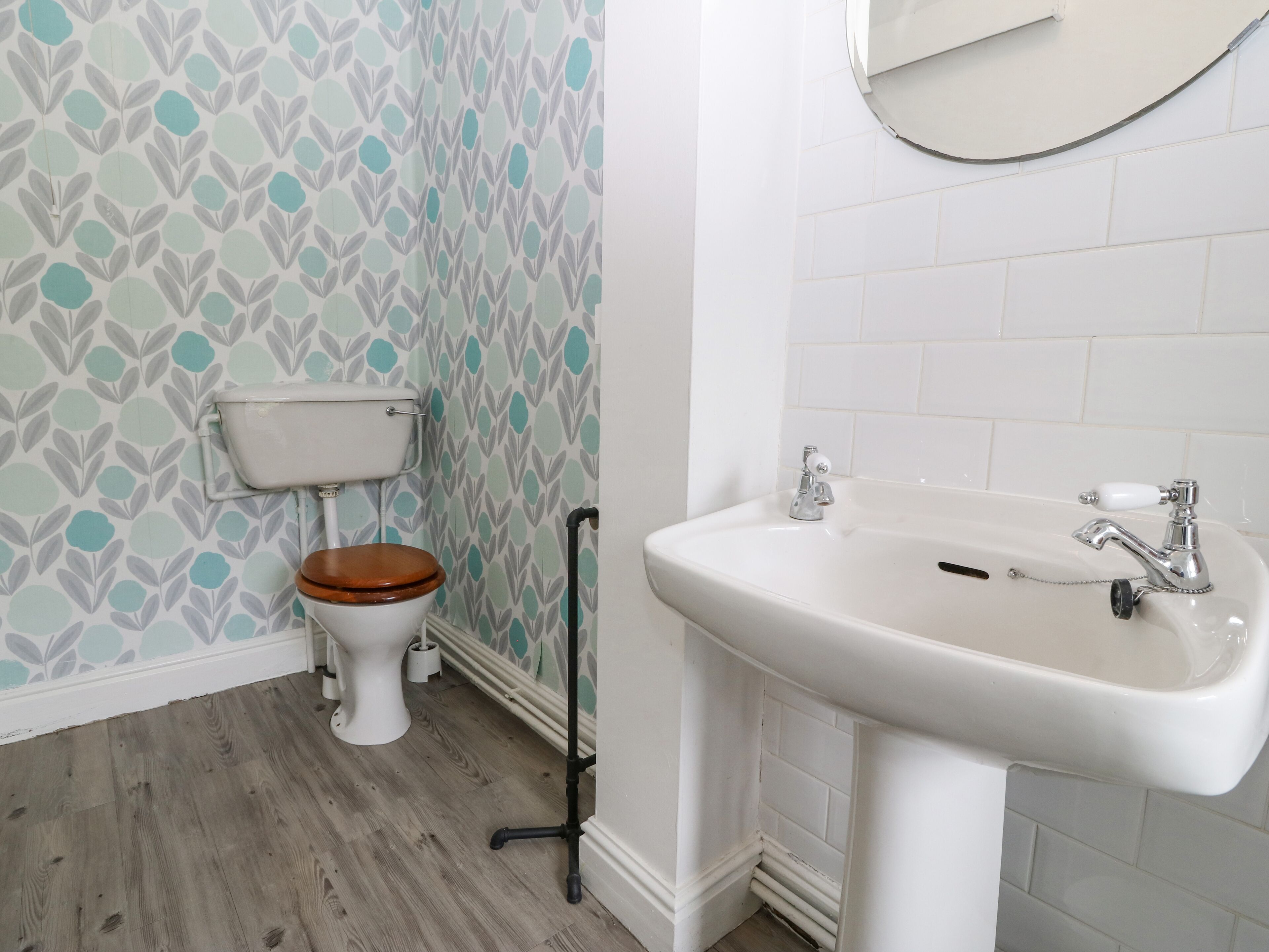 Un baño con inodoro, lavabo y suelo de madera.