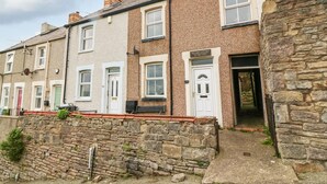 A row of terraced houses with stone walls and a mix of white and brown facades. - Pebblestone Cottage (Llandudno)
