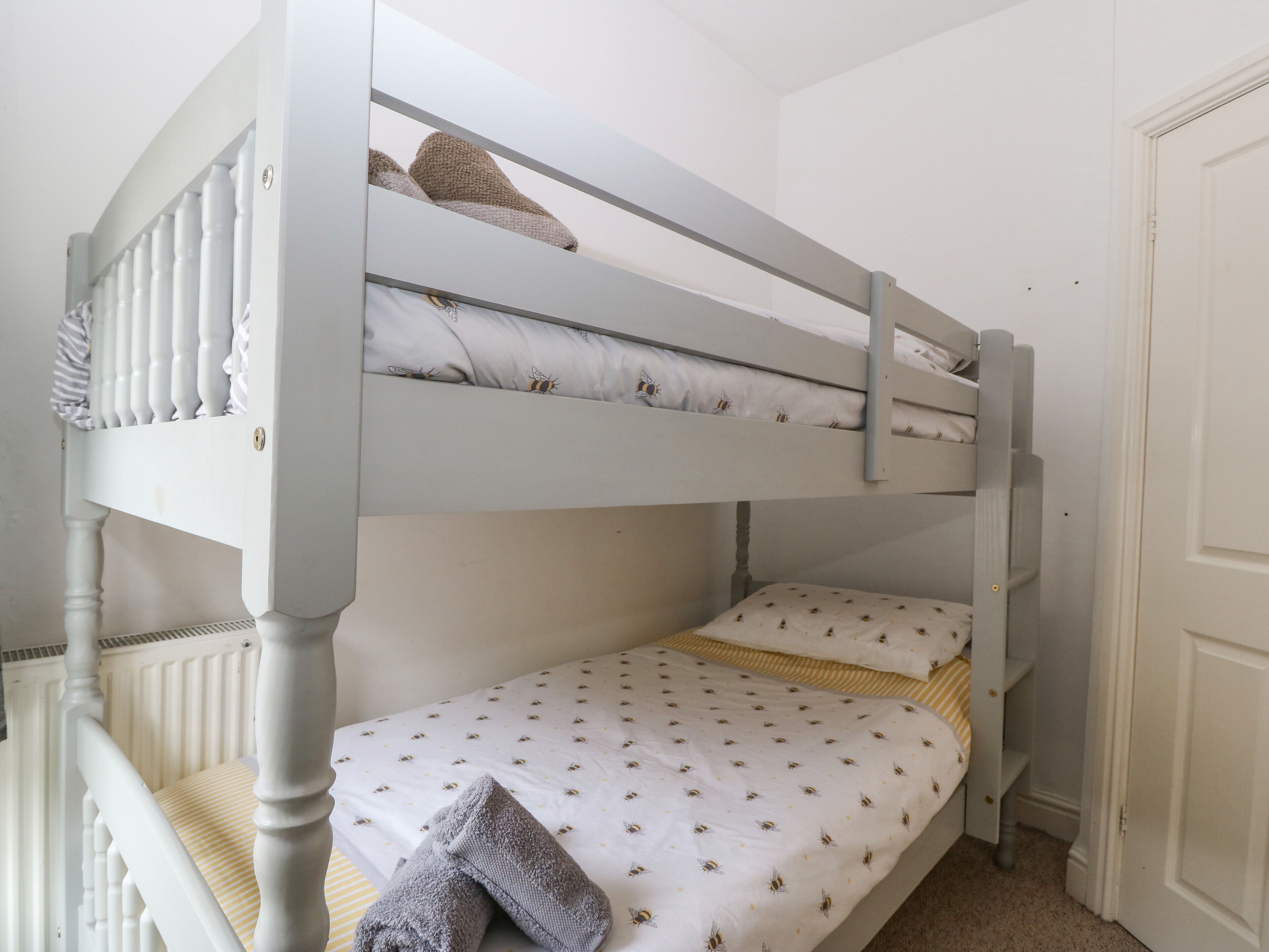A bunk bed with a white headboard and a lower bed with a patterned bedspread.