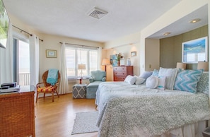 A bedroom with a bed, a chair, a table, and a dresser.