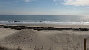 Une plage avec un mur de pierres et des empreintes de pas dans le sable.