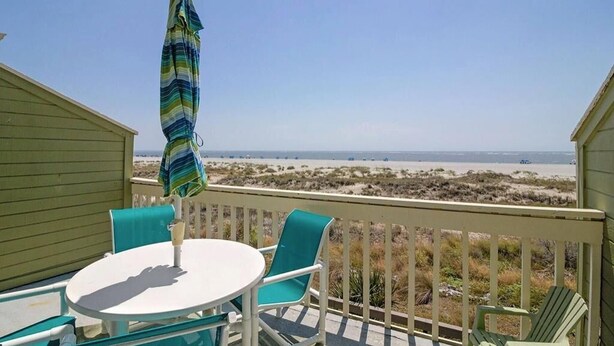 Un balcon avec une table et des chaises, donnant sur une plage.
