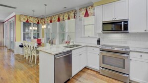 Una cocina moderna con armarios blancos, electrodomésticos de acero inoxidable y suelo de madera.