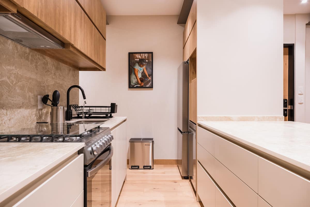 A modern kitchen with wooden cabinets, stainless steel appliances, and a marble countertop.