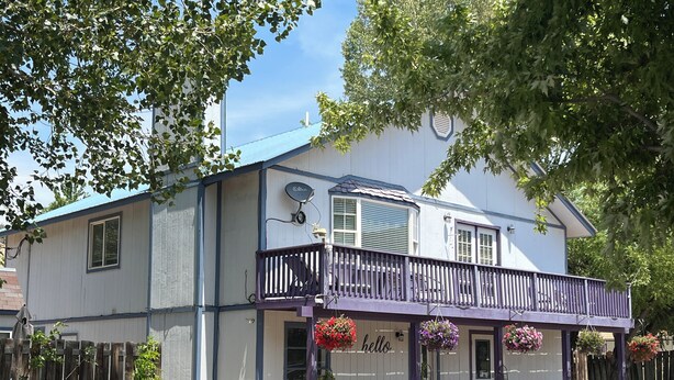 A two-story building with a balcony, a 'hello' sign, and potted plants. - DOWNTOWN DOLORES COLORADO w/river access - Stay at Cozy Comfort Inn, Dolores, CO (Dolores)