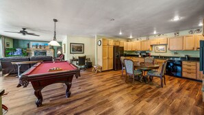A spacious living area with a pool table, a dining table with chairs, and a kitchen with wooden cabinets. - DOWNTOWN DOLORES COLORADO w/river access - Stay at Cozy Comfort Inn, Dolores, CO (Dolores)