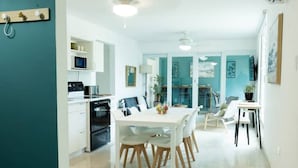 Une cuisine moderne avec des meubles blancs, un four à micro-ondes et une cuisinière. On y trouve également un coin repas avec une table et des chaises blanches.