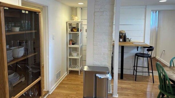 A compact kitchen with a wooden dining table, a small bar stool, and a trash bin. - Kingston 3 Bedroom 1 Bath Near the Rondout (Kingston)