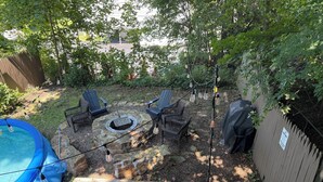 A backyard with a stone fire pit, two Adirondack chairs, a blue inflatable pool, and a wooden fence. - Kingston 3 Bedroom 1 Bath Near the Rondout (Kingston)
