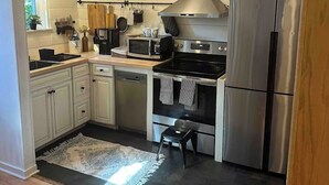 A modern kitchen with white cabinetry, stainless steel appliances, and a small stool. - Kingston 3 Bedroom 1 Bath Near the Rondout (Kingston)